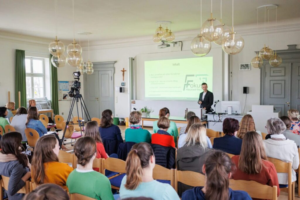 Referent hält einen Fachvortrag vor Teilnehmenden in einem Seminarraum.